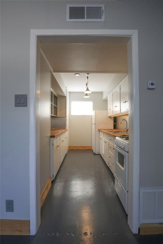 Kitchen featuring white appliances, finished concrete floors, and white cabinetry | Image 8