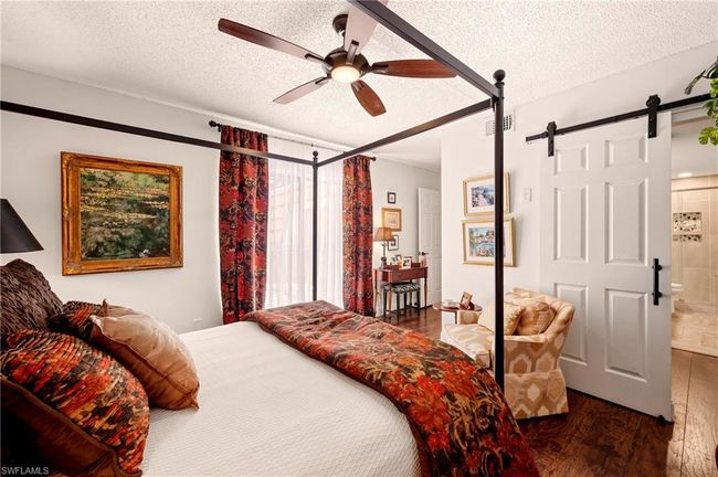 Bedroom featuring wood-type flooring, a barn door, a textured ceiling, a ceiling fan, and connected bathroom | Image 24
