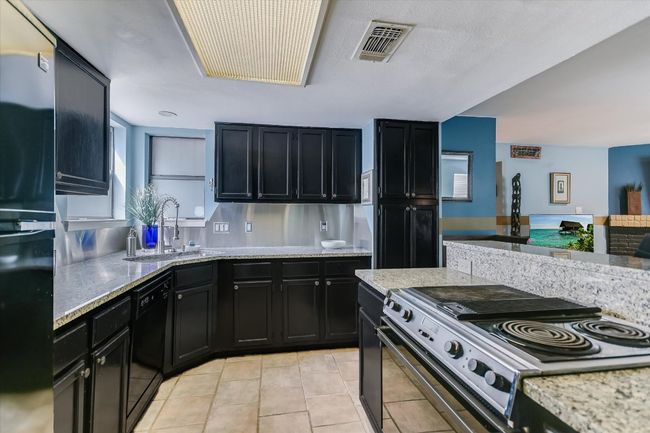 The kitchen is equipped with ample cabinetry, including a full-size pantry cabinet, granite countertops, and a breakfast bar that opens to the living room, fostering a sense of connection. | Image 5