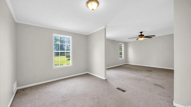 Carpeted spare room with ornamental molding, a ceiling fan, and a textured ceiling | Image 17