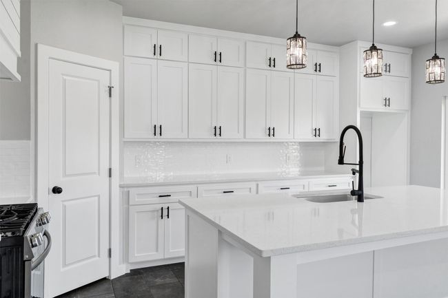 Kitchen featuring a sink, gas stove, white cabinets, decorative light fixtures, and tasteful backsplash | Image 14