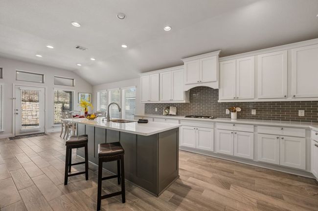 Kitchen with light countertops, a breakfast bar area, visible vents, and a sink | Image 5