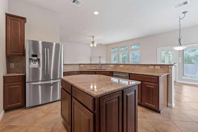 Kitchen featuring stainless steel appliances, granite counters, vaulted ceiling, backsplash, and tile flooring | Image 4