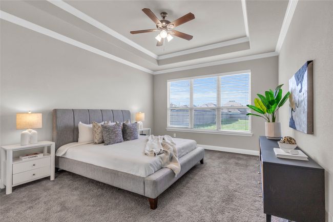 Carpeted bedroom with a tray ceiling, crown molding, baseboards, and ceiling fan | Image 15