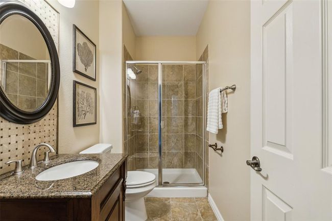 Bathroom with a shower with door, toilet, tile floors, and large vanity | Image 13