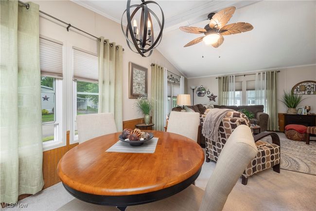 Carpeted dining space featuring vaulted ceiling, plenty of natural light, crown molding, and ceiling fan | Image 23