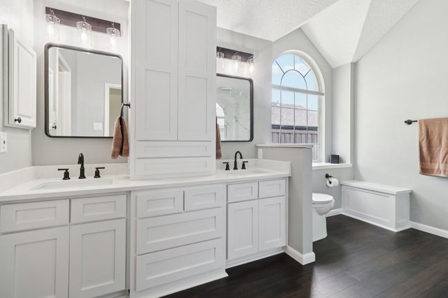 Bathroom featuring toilet, vaulted ceiling, double vanity, baseboards, and wood finished floors | Image 21