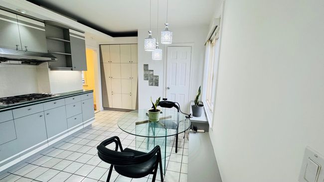 Kitchen featuring exhaust hood, gas cooktop, open shelves, decorative backsplash, and light tile patterned floors | Image 5