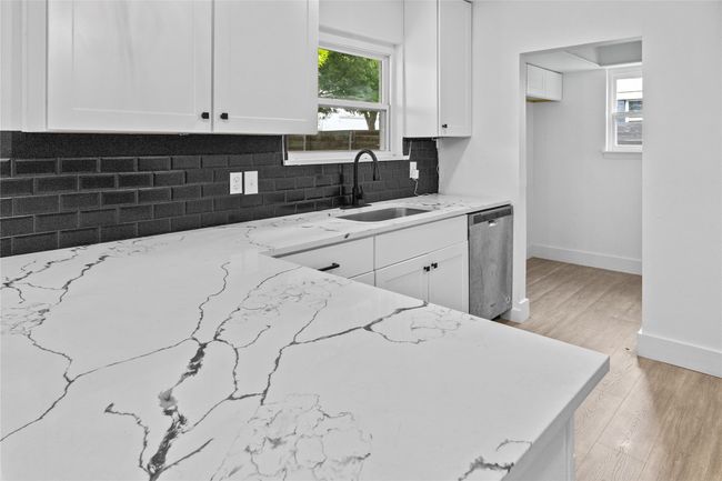 Kitchen with dishwasher, a sink, light stone counters, white cabinets, and backsplash | Image 8