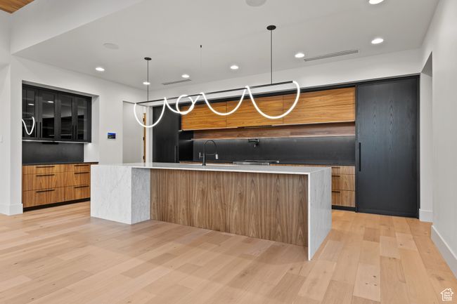 Kitchen with a large island with sink, visible vents, a sink, modern cabinets, and light wood-type flooring | Image 29
