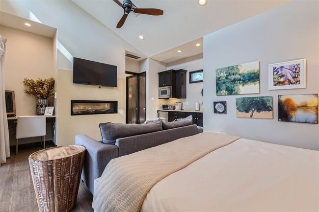 Bedroom with lofted ceiling, recessed lighting, a glass covered fireplace, ceiling fan, and wood finished floors | Image 6