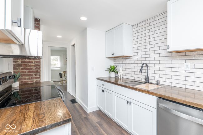 kitchen with backsplash, dark wood-style floors, stainless steel appliances, and a sink | Image 13