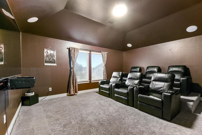 The large media room is designed for the ultimate viewing experience, featuring built-in surround sound speakers in the ceiling, tiered seating, and dark tones that create the perfect movie theater ambiance right at home. It’s the ideal space for enjoying films, sports, or gaming in comfort and style at home. | Image 26