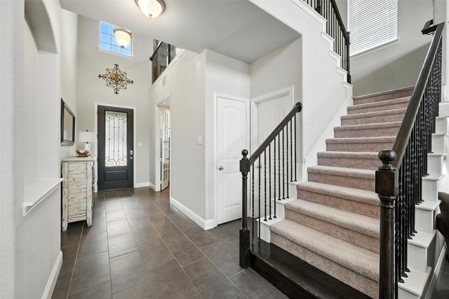 Foyer entrance with stairway, dark tile patterned flooring, and a high ceiling | Image 6