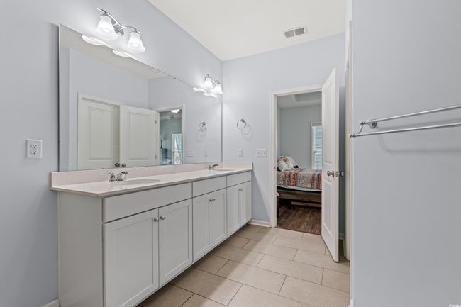 Master bathroom featuring a stall shower with glass doors, double vanity, and a walk in closet. | Image 15