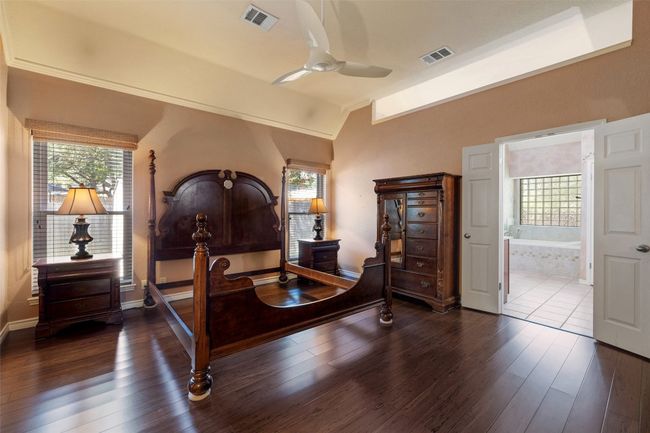 Bedroom with vaulted ceiling, multiple windows, dark wood-type flooring, ensuite bath, and baseboards | Image 21