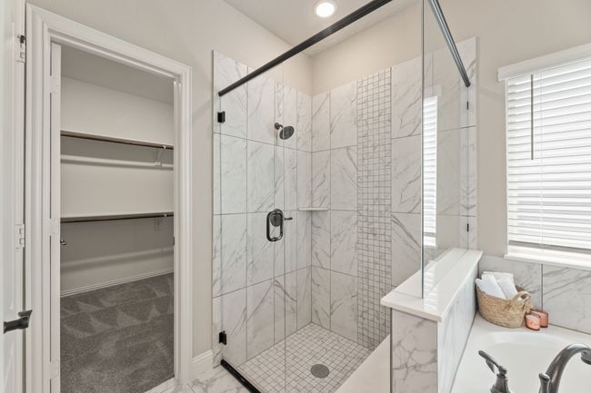Bathroom with a shower stall, a bath, marble look tiles, and a walk in closet | Image 17