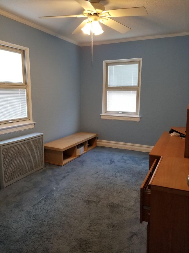 Unfurnished bedroom with radiator, carpet, baseboards, ceiling fan, and crown molding | Image 8