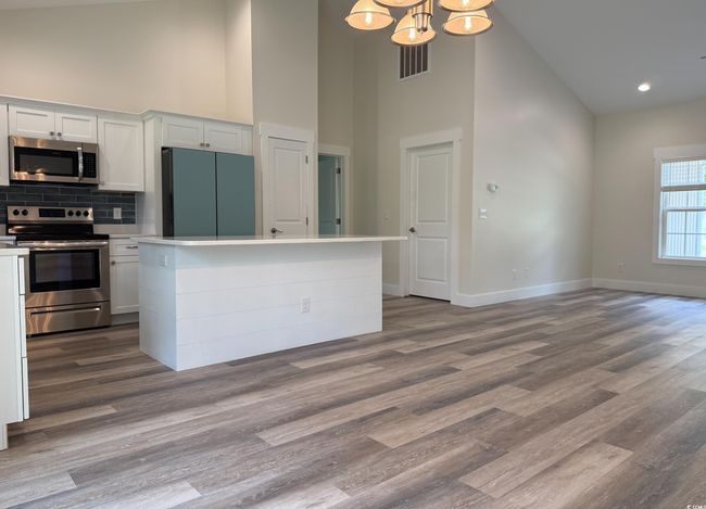 Kitchen with stainless steel appliances, high vaulted ceiling, a chandelier, tasteful backsplash, and white cabinetry | Image 11