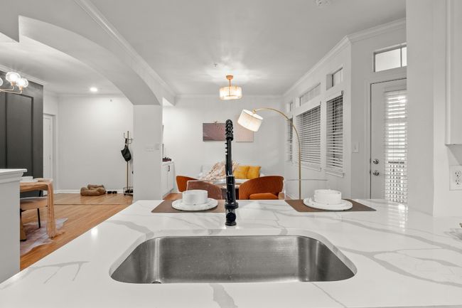 Interior details featuring arched walkways, wood finished floors, a sink, ornamental molding, and decorative light fixtures | Image 5