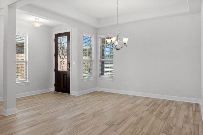 Foyer featuring a chandelier, light wood-style flooring, a raised ceiling, and baseboards | Image 10