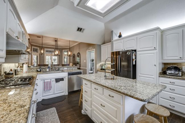 Kitchen featuring visible vents, a sink, stainless steel appliances, a breakfast bar area, and lofted ceiling | Image 12