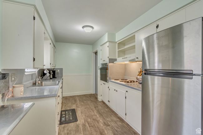 Kitchen with oven, a sink, freestanding refrigerator, wainscoting, and white electric stovetop | Image 7