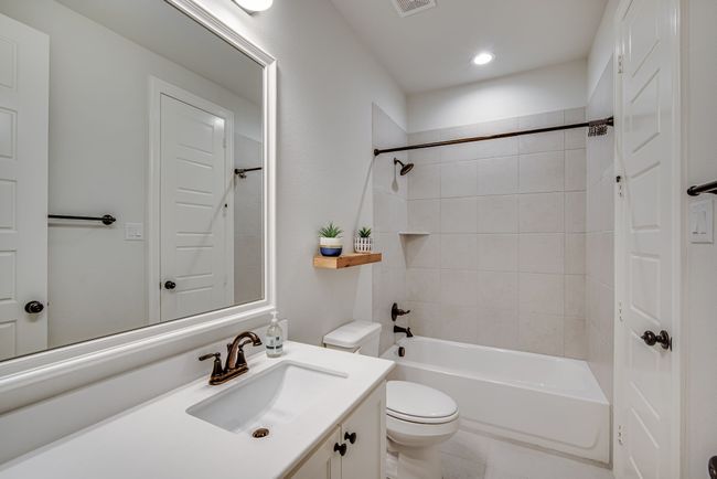 Full bathroom featuring toilet, tiled shower / bath combo, vanity, and tile patterned floors | Image 24
