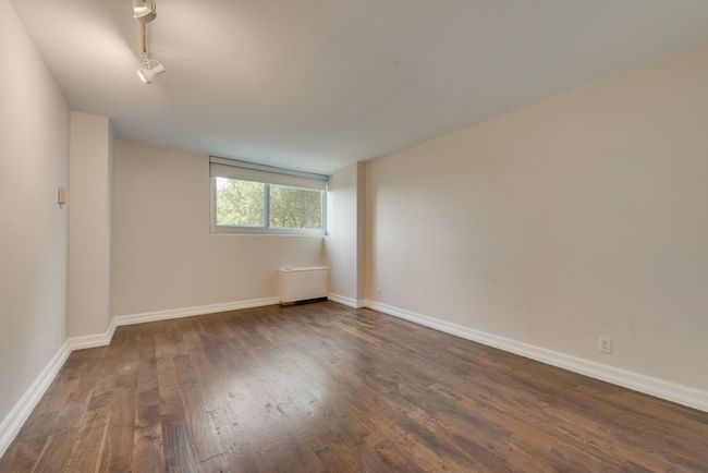 Primary bedroom features the same wood flooring; has roller shade. | Image 8