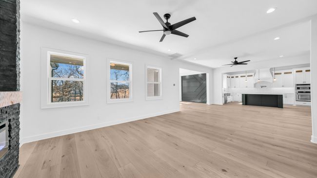 Unfurnished living room with recessed lighting, ceiling fan, a fireplace, and light wood-style floors | Image 10