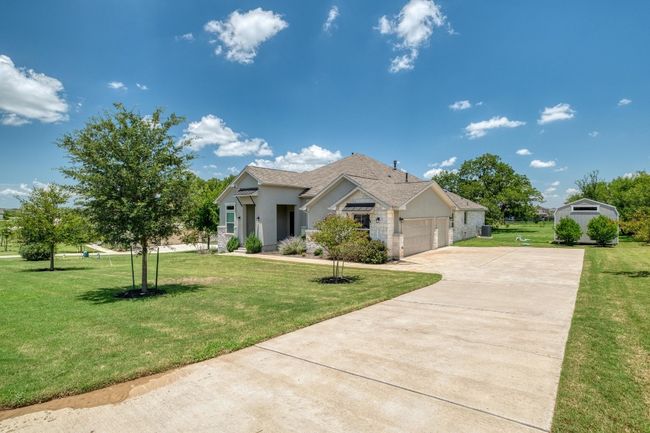 View of front facade featuring driveway, a garage, a front lawn, stucco siding, and a shingled roof | Image 4