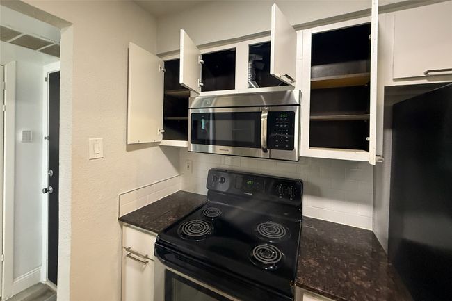 Kitchen with electric range, stainless steel microwave, tasteful backsplash, and white cabinetry | Image 14