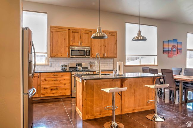 Kitchen with appliances with stainless steel finishes, decorative backsplash, dark tile patterned floors, and a sink | Image 8