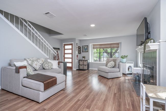 Living area featuring light wood finished floors, a tile fireplace, visible vents, and stairway | Image 11
