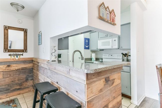 Entryway has a breakfast bar wrapped with wood paneling. | Image 4