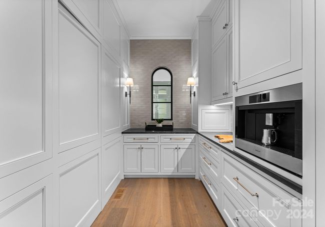 Push to open walk-in pantry, extensive storage, and Wolf espresso machine all included in the scullery. | Image 13