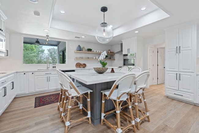 Kitchen with oversized quartz island. Custom open shelves. Double ovens | Image 11