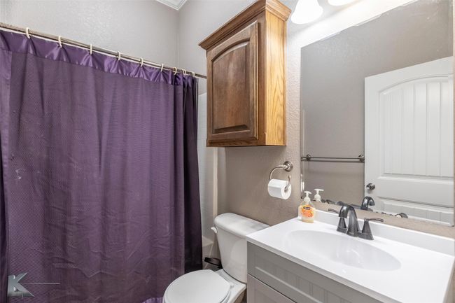 Full bath with a textured wall, vanity, toilet, and a shower with curtain | Image 23