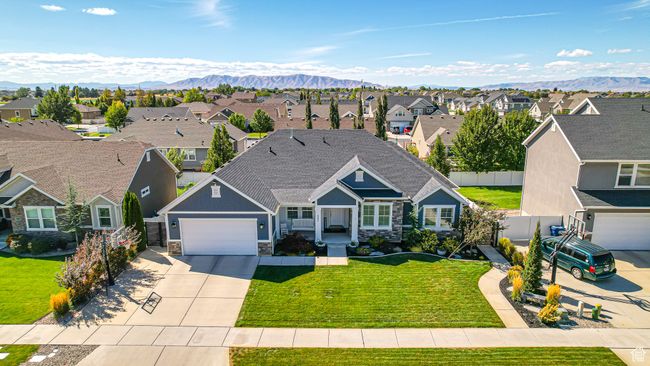 Traditional-style house featuring concrete driveway, fence, stone siding, a residential view, and a front yard | Image 58