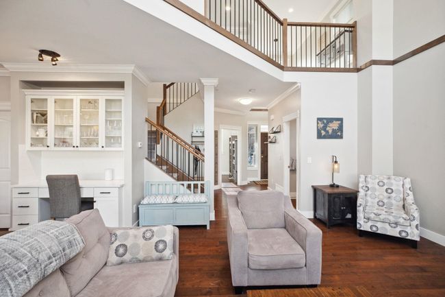 Living room with built in desk, dark wood-style flooring, crown molding, and stairway | Image 7