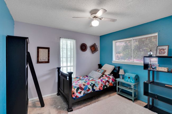 Bedroom featuring multiple windows, baseboards, a textured ceiling, and a ceiling fan | Image 16
