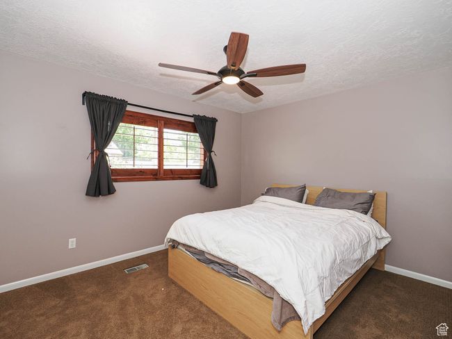 Bedroom featuring baseboards, a textured ceiling, carpet, and a ceiling fan | Image 24