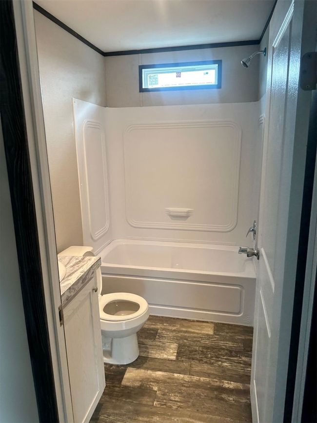Bathroom featuring toilet, wood finished floors, vanity, and shower / bathtub combination | Image 8