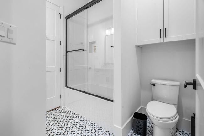 Full bath with toilet, shower / bath combination with glass door, baseboards, and tile patterned flooring | Image 17