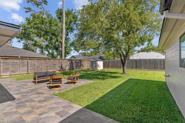 Step outside to the expansive custom-tiled back patio and lush backyard. | Image 27