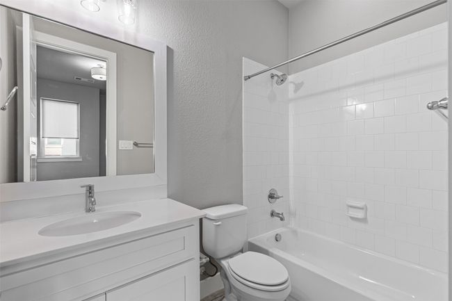 Bathroom featuring a textured wall, toilet, vanity, and shower / bath combination | Image 16