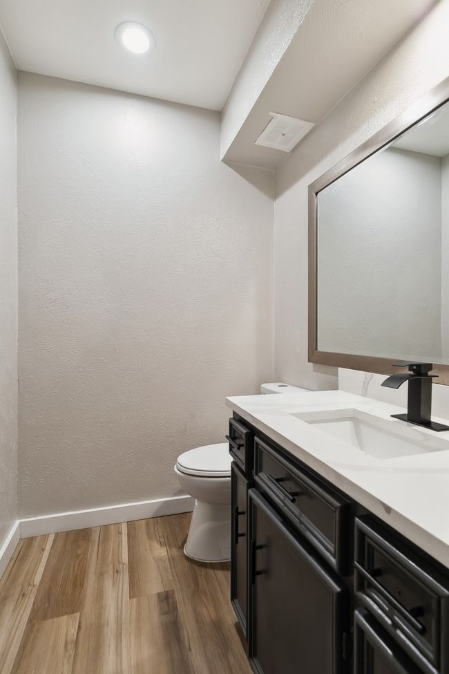Half bath featuring baseboards, toilet, recessed lighting, wood finished floors, and vanity | Image 17