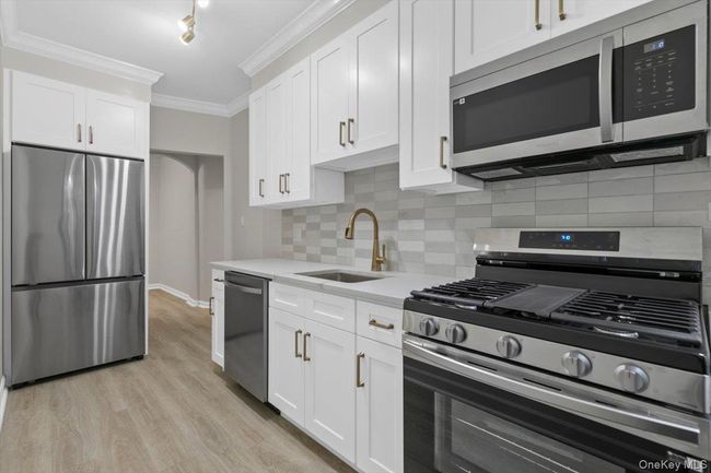 Kitchen with appliances with stainless steel finishes, decorative backsplash, ornamental molding, and white cabinets | Image 6