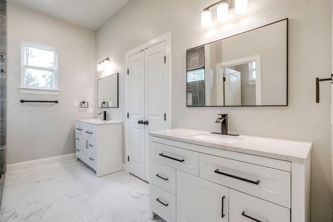 Bathroom featuring marble finish floor, baseboards, tiled shower, two vanities, and a sink | Image 19