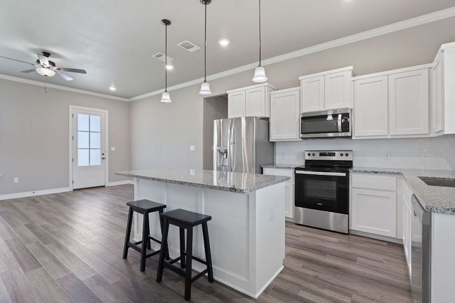 Kitchen with stainless steel appliances, a center island, crown molding, ceiling fan, and decorative backsplash | Image 13